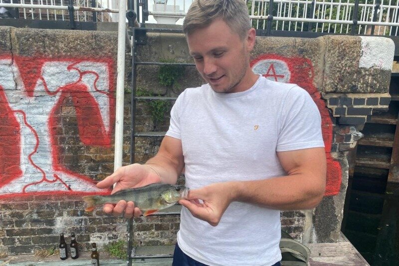 Me holding a small perch on the canal by Hackney Wick
