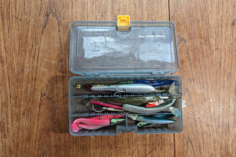 Savage Gear's medium sized lure box full of a variety of lures on a wooden table