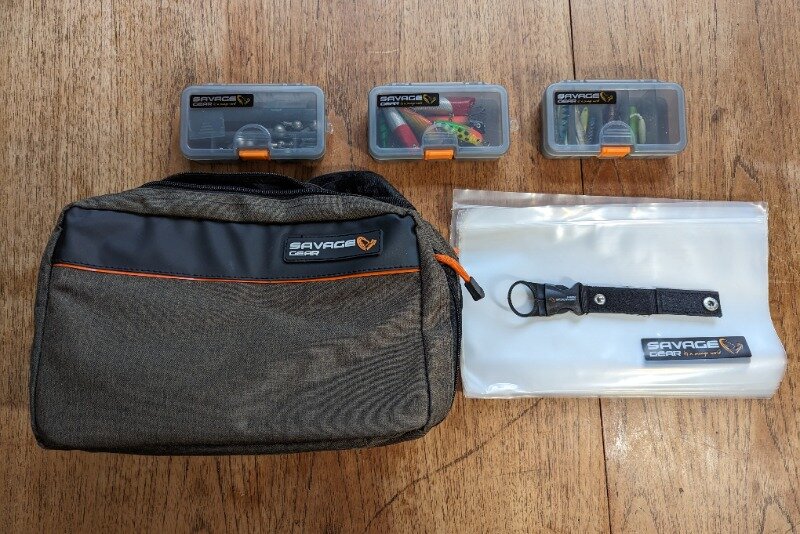 The lure boxes and sleeves of Savage Gear's lure fishing shoulder bag laid on a wooden table