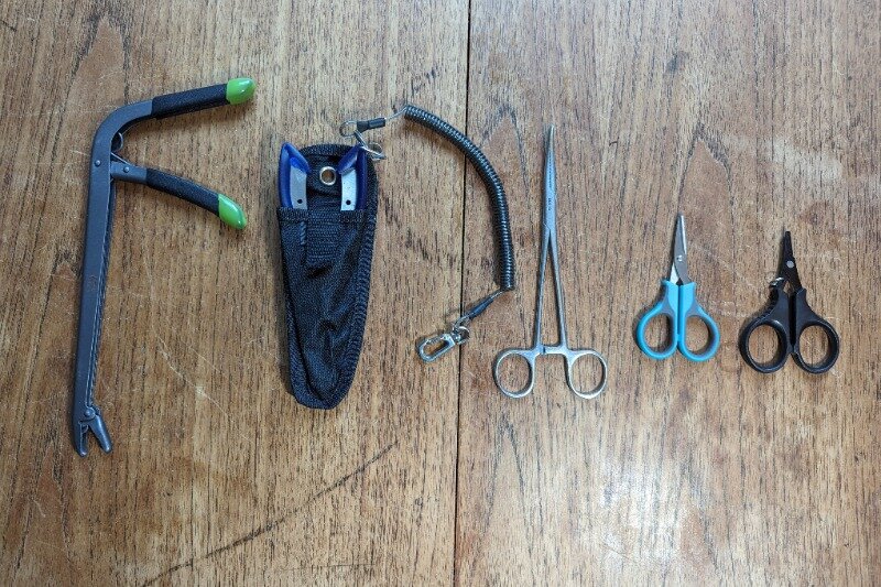 A variety of pliers and scissors laid out on a wooden table