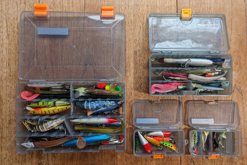 My three lure boxes full of lures - large, medium and small on a wooden table