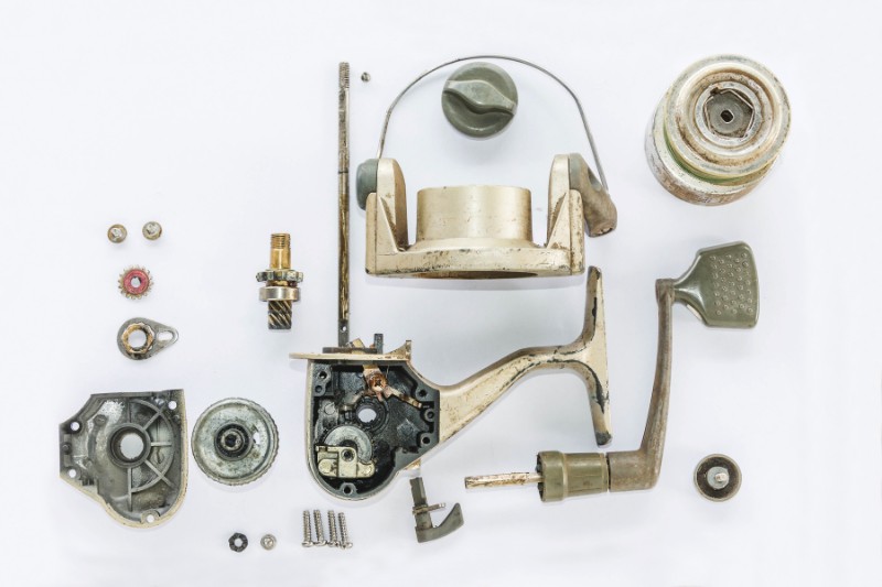 A fishing reel broken down with components placed on a white background