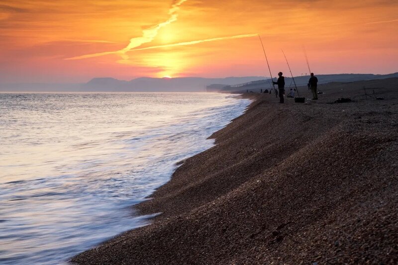 Photo of anglers fishing on Chesil Beach at sunset