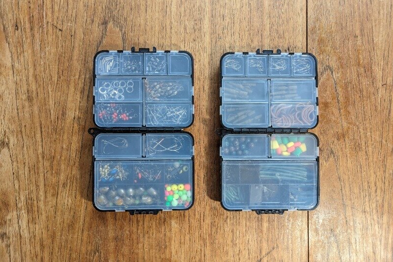 Two fully stocked terminal tackle boxes on a wooden table