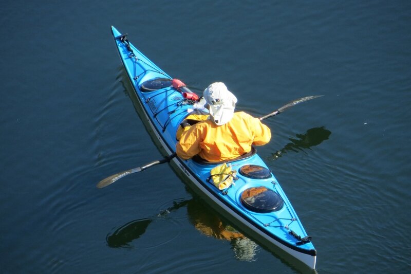 Man fishing in a sit-in blue kayak on the ocean