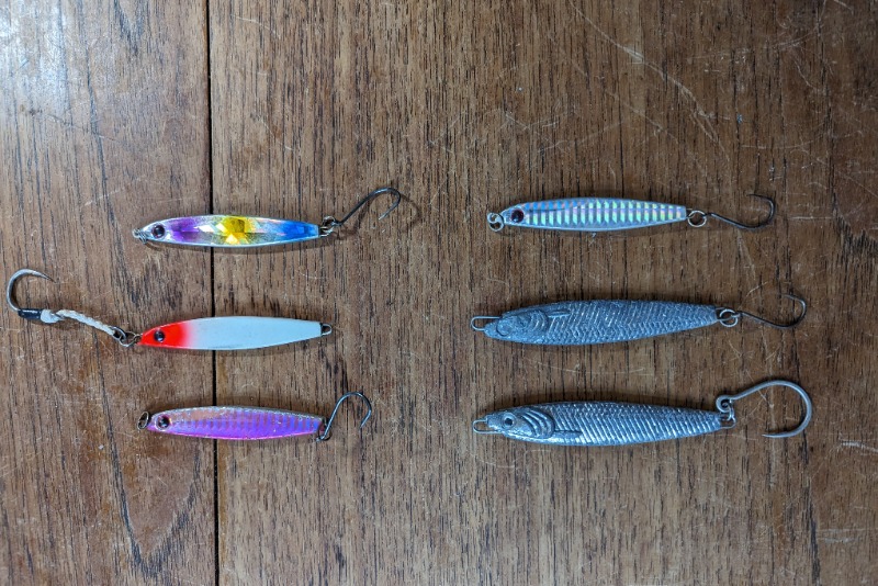 Six metal lures currently in our sea fishing lure box on a table