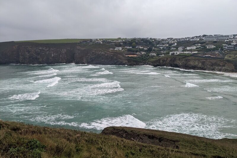 A view over the beach at Mawgan Porth at high tide with a spring tide rolling in